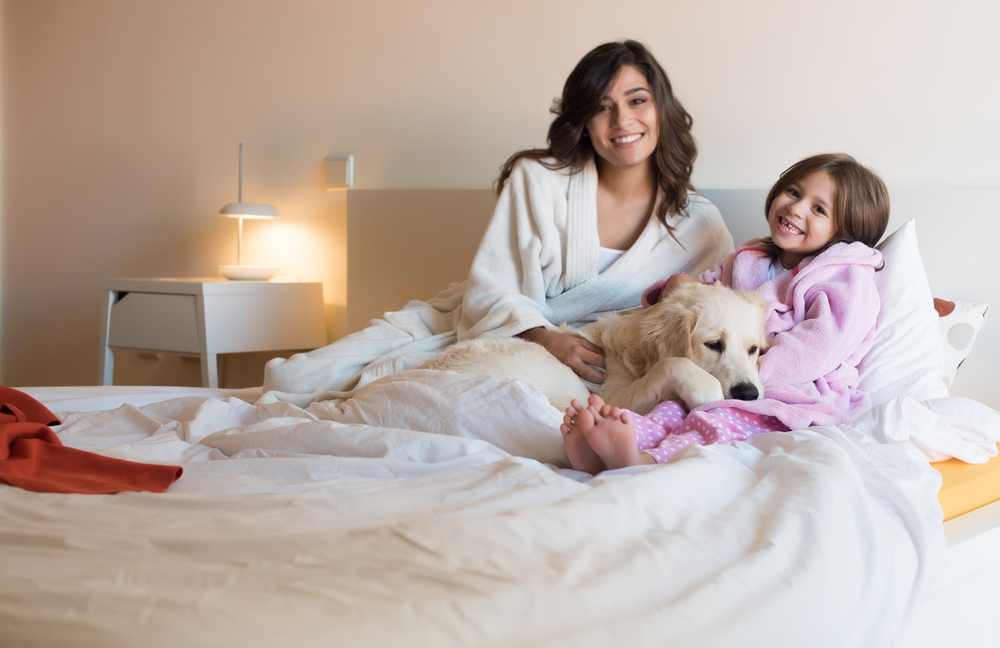 mamma e figlia con il cane sul letto